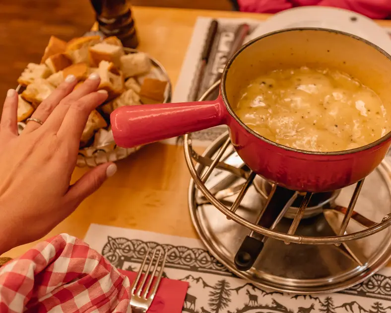 Me reaching for some bread to dip in fondue at Swiss Chuchi. One of the best places to eat in this Zurich layover guide. 