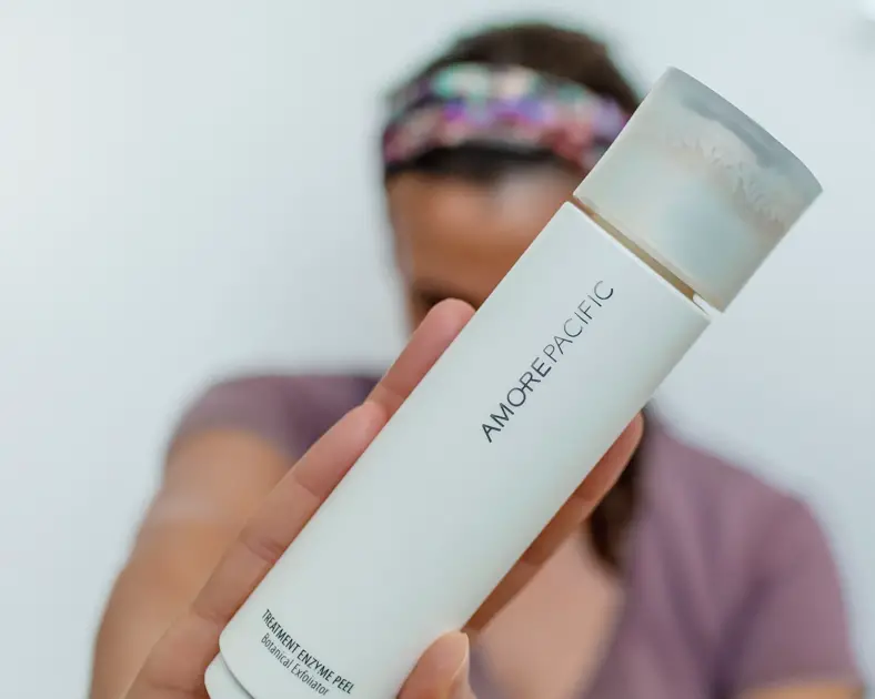 Me holding  AmorePacific Treatment Enzyme Peel Cleansing Powder bottle one of the best Exfoliating face masks.