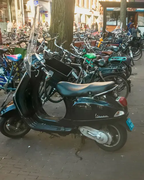A line of motorcycles and bikes on the streets of Amsterdam