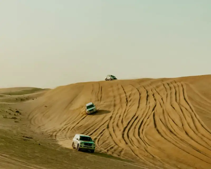 3 cars going down a sand dune during my Abu Dhabi day trip from Dubai