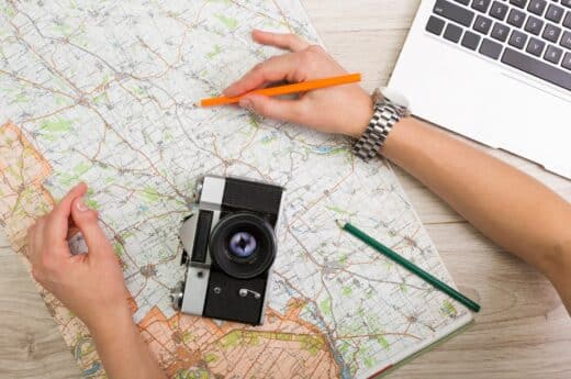 Traveling hacks photo of someone planning a trip with a map and laptop.