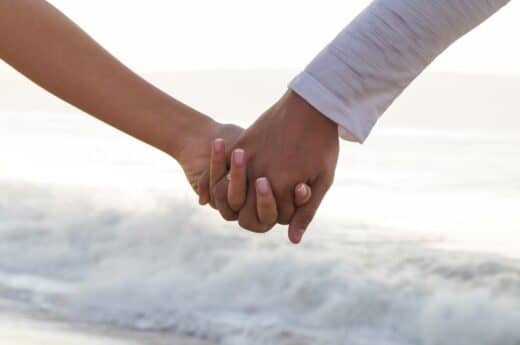 Photo for romantic things to do in Miami of a couple holding hands at the beach.