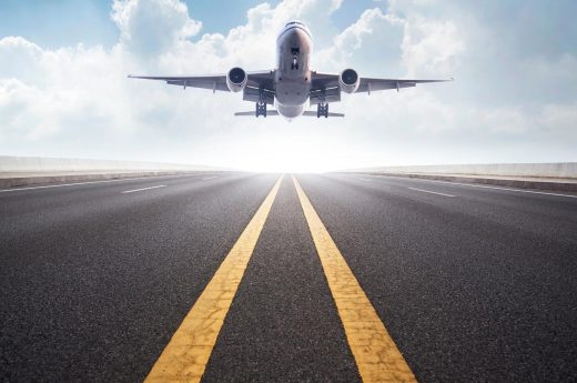 Flying captions photo of an airplane landing on the runway.